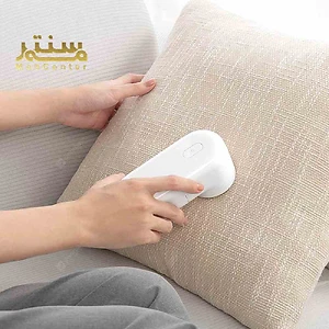 دستگاهی کوچک و سفید در حال تمیز کردن یک بالش روشن.
