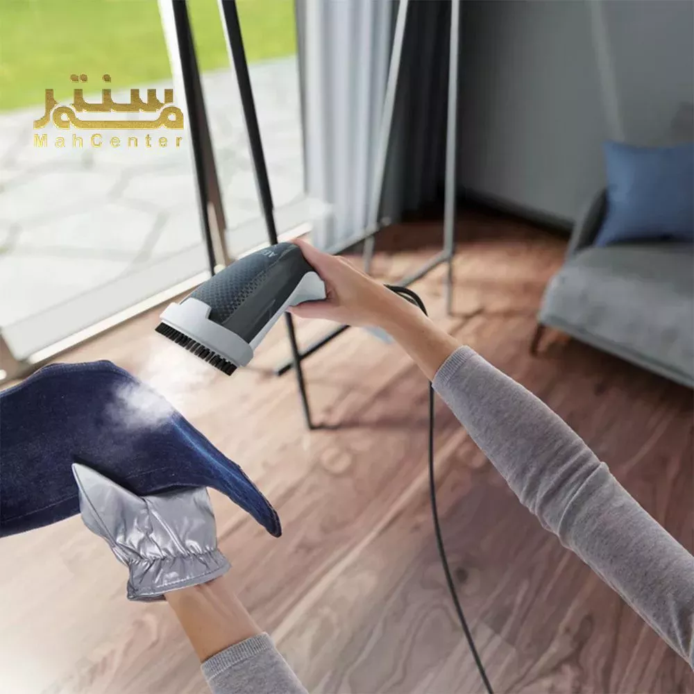 "یک بخارگر دستی در حال بخاردهی به لباس، با استفاده از دستکش محافظ حرارت."