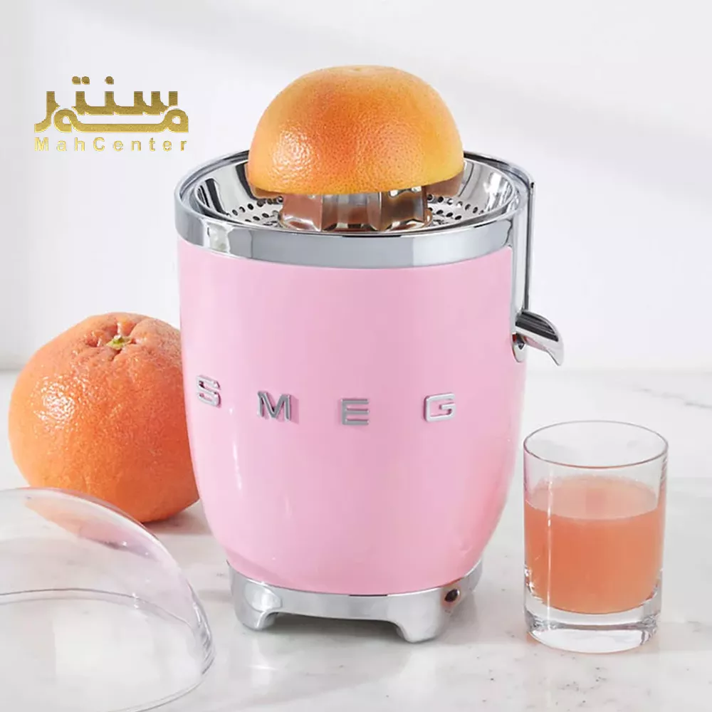 `آبمیوه‌گیری صورتی رنگ برند SMEG با طراحی شیک و میوه گریپ‌فروت برای تهیه آبمیوه تازه.`