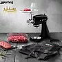 یک آسیاب گوشت مشکی رنگ SMEG با طراحی کلاسیک در حال چرخ کردن گوشت برای تهیه برگر، همراه با پیشبند مشکی رنگ.