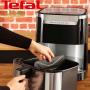 Alt: "تصویری از یک سرخ‌کن تفال Easy Fry & Grill XXL در حال استفاده، با دستی که قسمت داخلی دستگاه را جابجا می‌کند. دستگاه بر روی پیشخوان آشپزخانه قرار دارد."