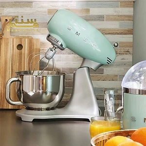 مخلوط کن ایستاده SMEG 50s یکپارچهسازی با رنگ پاستیلی نعنایی، با یک کاسه مخلوط کن شیشه ای و یک آبمیوه گیری در پس زمینه.