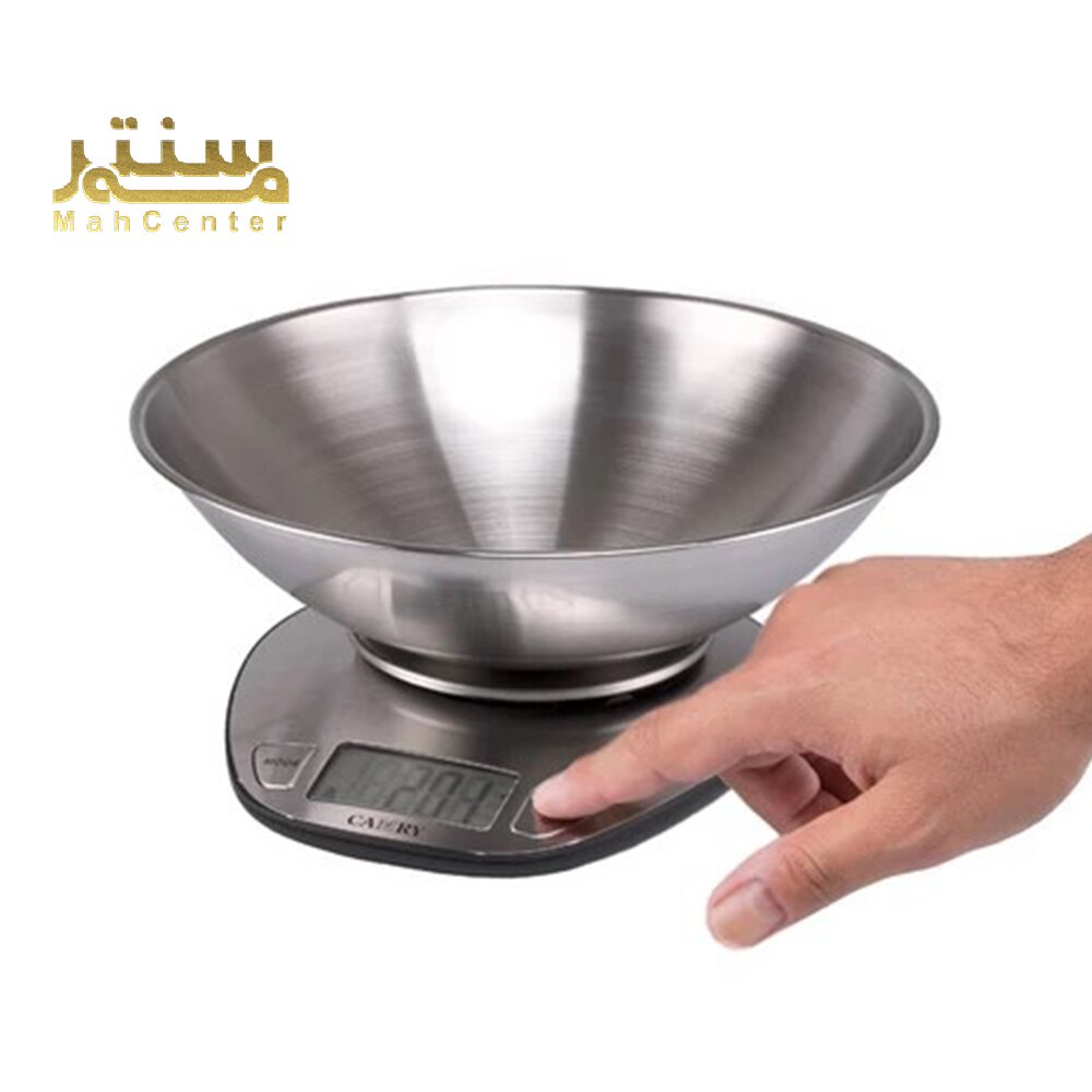 یک ترازوی آشپزخانه الکترونیکی Camry 4360 با یک کاسه فولادی ضد زنگ در بالا، روی یک سطح سفید قرار دارد. یک دست در حال فشار دادن دکمه صفر کردن ترازو است