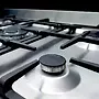 تصویر نزدیک از اجاق گاز با سطح استیل براق و شعله‌پخش‌کن‌های مدرن ساخت ایتالیا.