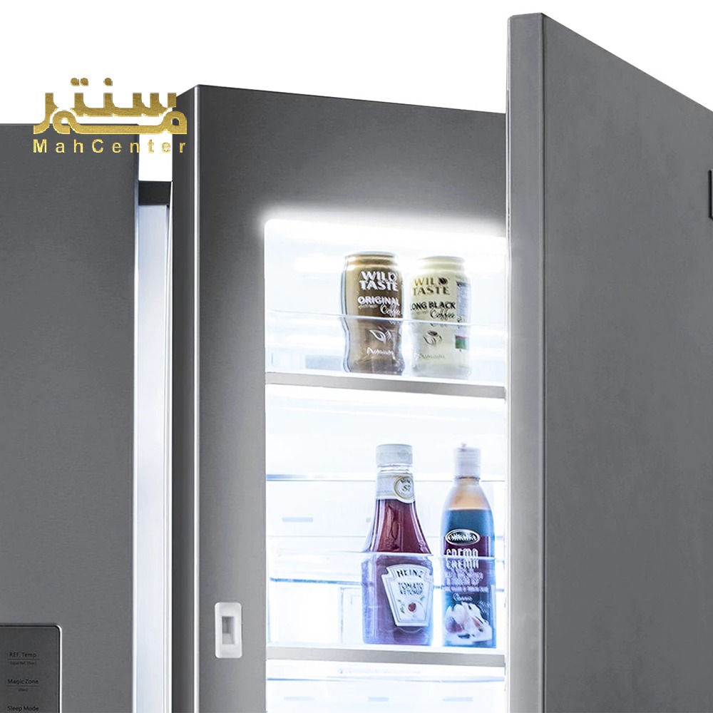 داخل یخچال با درب باز، نمایش قفسه‌ها شامل کنسروها و بطری‌های سس و نوشیدنی در نور سفید روشن.