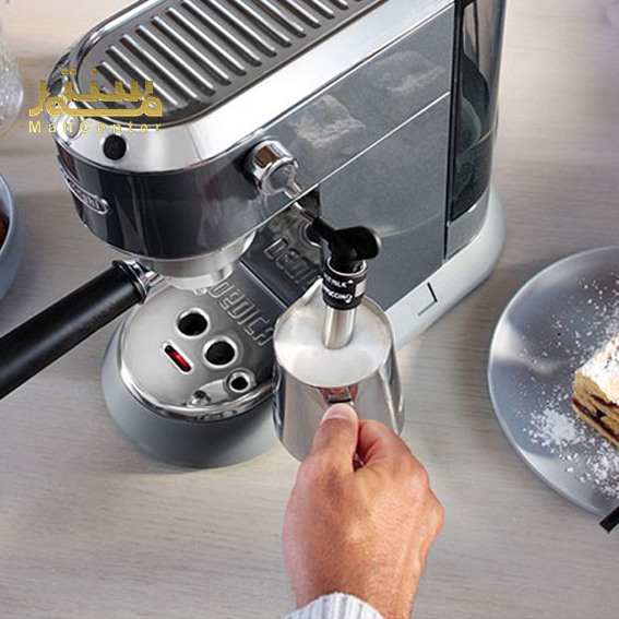 یک دستگاه اسپرسو De'Longhi Dedica مشکی و نقره ای در پس زمینه سفید نمایش داده می شود. یک فنجان قهوه در زیر دستگاه قرار دارد و یک دست در حال چرخاندن دستگیره است.