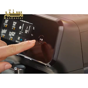 یک دست در حال فشار دادن یک دکمه روی یک دستگاه قهوه ساز فیلیپس نشان داده شده است. دستگاه قهوه ساز مشکی است و دارای یک صفحه نمایش لمسی است.