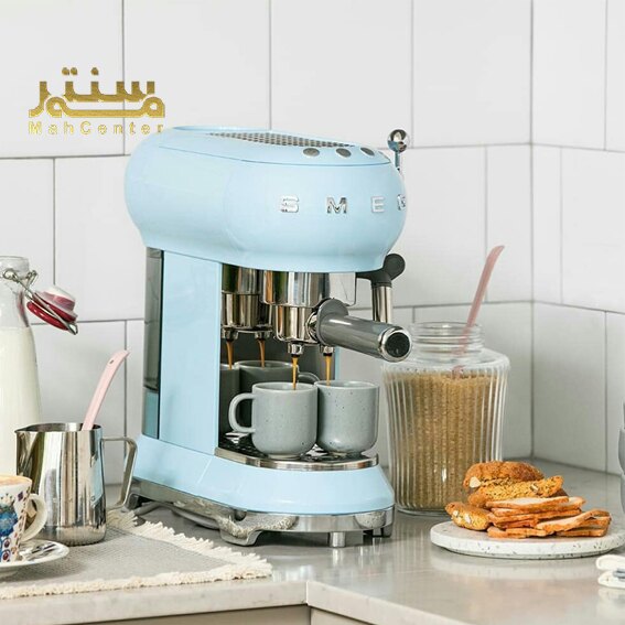 تصویر نشان‌دهنده یک دستگاه قهوه‌ساز مدرن و زیبای برند SMEG با رنگ آبی است که در یک محیط آشپزخانه قرار گرفته است.