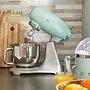 مخلوط کن ایستاده SMEG 50s یکپارچهسازی با رنگ پاستیلی نعنایی، با یک کاسه مخلوط کن شیشه ای و یک آبمیوه گیری در پس زمینه.