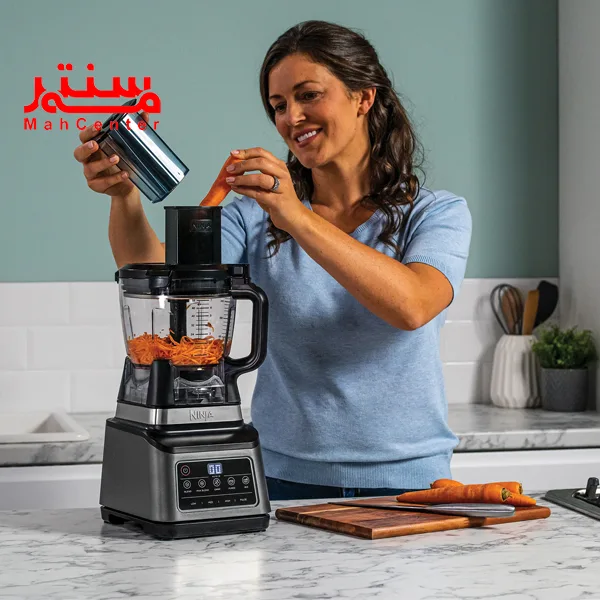 یک خانم با لباس آبی رنگ که در حال رنده کردن هویج با غذاساز نینجا bn800 است.