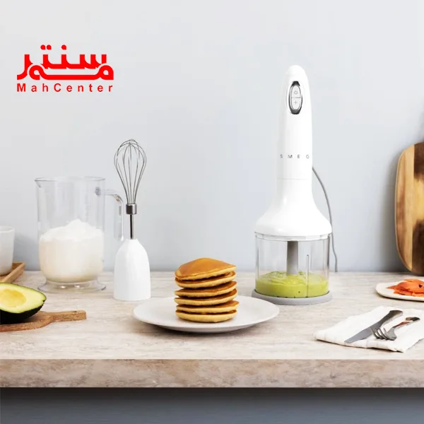 خردکن اسمگ مدل hbf03 سفید که در آن سس پسته است، در کنار آن هم دسته همزن دستی و جلوی آن بشقاب سفیدی که در آن 6تا پنکیک است.