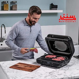 مردی در حال گریل کردن استیک‌ها با یک گریل برقی در یک آشپزخانه مدرن.